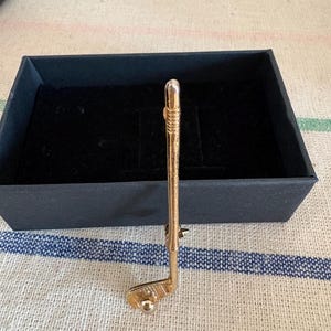 A vintage gold golf club tie pin, brooch, lapel pin