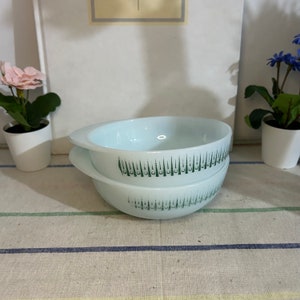 May include: Two white glass bowls with a light blue interior and green vertical stripe design. Each bowl has a handle on either side. The bowls are stacked on top of each other.