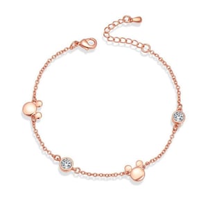 Op de afbeelding: Een roségouden armband met een delicate ketting en drie bedels. De bedels zijn twee Mickey Mouse-koppen en een helder kristal.