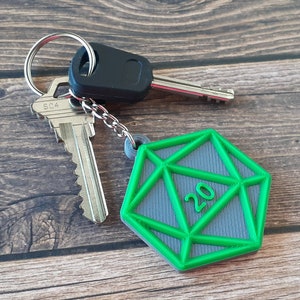 May include: A green and gray 20-sided die keychain attached to a silver key with a black and silver key fob.