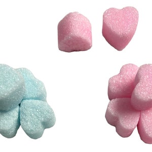May include: A group of light blue and pink heart-shaped foam packing peanuts. The peanuts are arranged in a cluster of five and a single peanut.