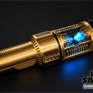 Peut inclure: Un sabre laser dor&eacute; et noir avec un design d&eacute;taill&eacute;. La section centrale pr&eacute;sente un cristal bleu brillant. Le sabre laser porte le texte "LSM SABERS" dans le coin inf&eacute;rieur droit.