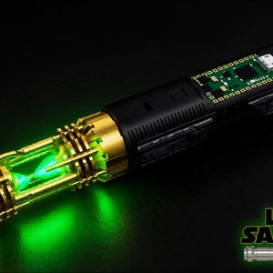 Peut inclure: Un sabre laser futuriste avec un design or et noir. La poign&eacute;e pr&eacute;sente une structure dor&eacute;e en forme de cage avec un c&oelig;ur vert brillant. Le manche est noir avec un d&eacute;tail de circuit imprim&eacute;. Le texte "LSM SABERS" est visible.