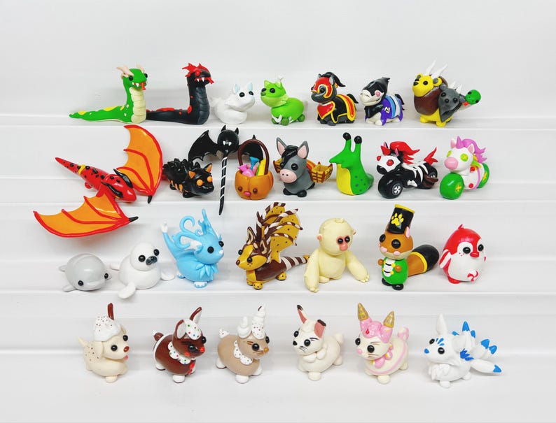 May include: A collection of 24 handmade polymer clay figurines, featuring a variety of animals, creatures, and characters. The figurines are brightly colored and detailed, with a whimsical and playful style.