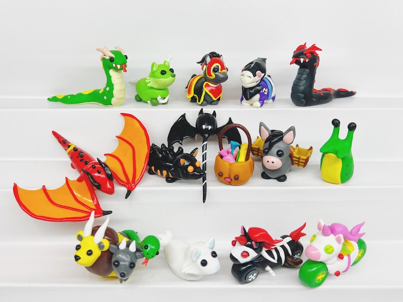 May include: A collection of 14 handmade polymer clay figurines, including a dragon, a bat, a snail, a unicorn, a donkey, a dragon, a bat, a snail, a unicorn, a donkey, a dragon, a bat, a snail, a unicorn, and a donkey. The figurines are painted in various colors, including red, green, black, white, and purple.