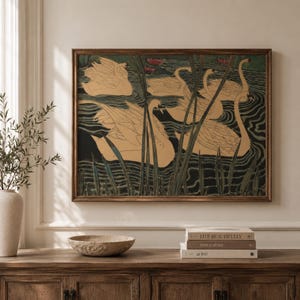 May include: A rectangular framed wall art print featuring a stylized illustration of several beige swans swimming in dark water among tall green reeds. The artwork displays a repeating pattern of birds with long necks and detailed feathers in a pond setting.