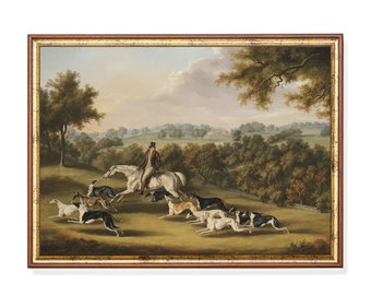 May include: An antique framed painting depicts a man on a white horse leading a pack of hounds across a grassy field. The artwork features a detailed landscape with trees, a distant house, and a cloudy sky. The frame is a warm brown color.