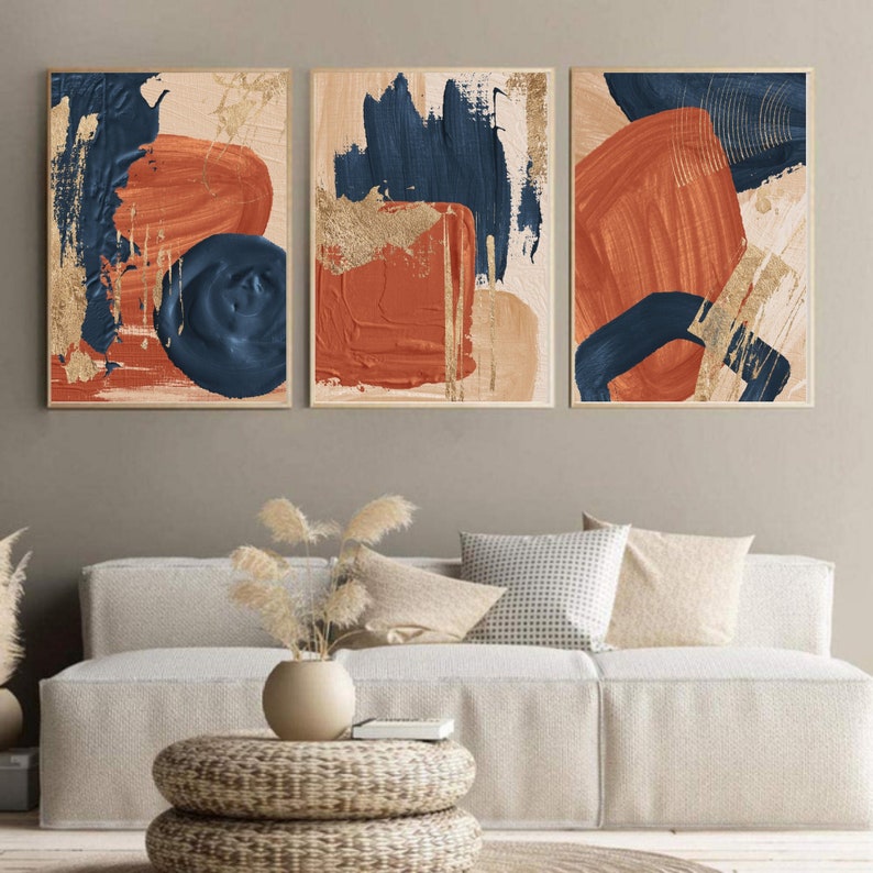 May include: Three abstract paintings with a modern minimalist design. The paintings feature bold strokes of blue, orange, and gold paint on a cream background.