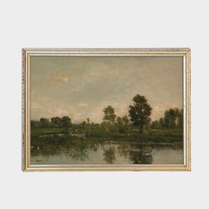 Pode incluir: Uma pintura de paisagem emoldurada que retrata uma cena tranquila de um rio com &aacute;rvores e um c&eacute;u nublado. A &aacute;gua &eacute; calma e reflexiva, com algumas folhas de l&iacute;rio flutuando na superf&iacute;cie.