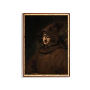 May include: A framed vintage portrait of a person wearing a brown hooded cloak. The artwork features a warm color palette with shades of brown and gold. The subject is looking down, creating a contemplative mood. The frame is gold.