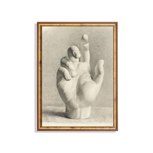 Könnte beinhalten: Ein gerahmter Vintage-Druck einer Hand, in Graustufen dargestellt. Die Hand ist mit dem nach oben ausgestreckten Zeigefinger dargestellt, die anderen Finger sind leicht gekrümmt. Der Rahmen ist in einem warmen Goldton gehalten und verleiht dem Kunstwerk einen klassischen Touch.
