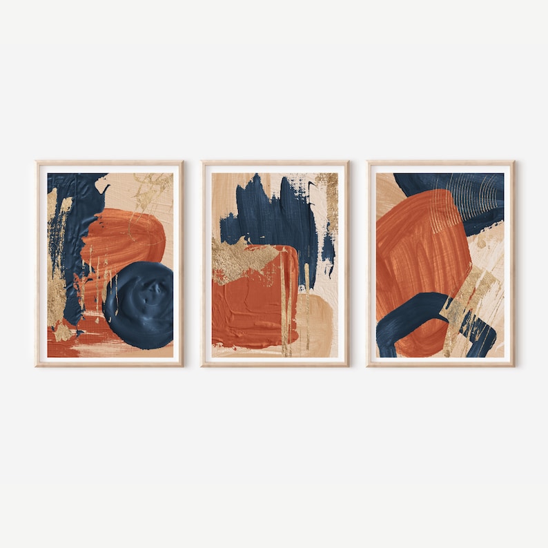 May include: Set of three abstract art prints featuring bold brushstrokes in shades of burnt orange, navy blue, and gold on a beige background.