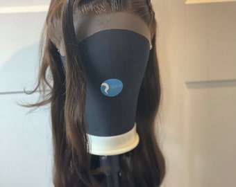 May include: A long, brown wig with loose waves styled in a high ponytail with a braid on top. The wig is on a mannequin head.