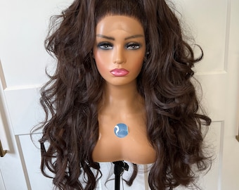 May include: A long, dark brown wig with loose curls styled in a high ponytail. The wig is on a mannequin head and is displayed on a black stand.