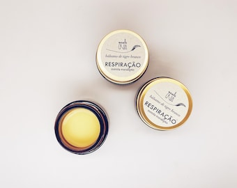 May include: Two gold-coloured metal containers with labels that read "bálsamo de tigre branco RESPIRAÇÃO menta eucalipto" and a third container with a yellow substance inside.