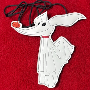 Puede incluir: Un personaje blanco de Zero de The Nightmare Before Christmas, con ojos negros, un collar rojo y una nariz de calabaza. El personaje est&aacute; sujeto a un cord&oacute;n negro. El fondo es rojo liso.