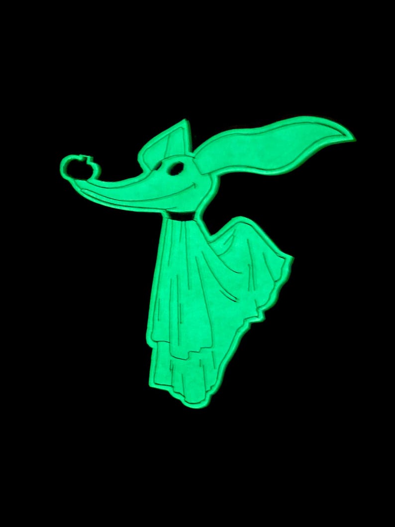 Puede incluir: Un personaje de perro fantasma de dibujos animados verde brillante con orejas grandes, una nariz larga y un collar negro. El personaje lleva una s&aacute;bana drapeada y tiene una expresi&oacute;n sonriente. El fondo es negro s&oacute;lido.
