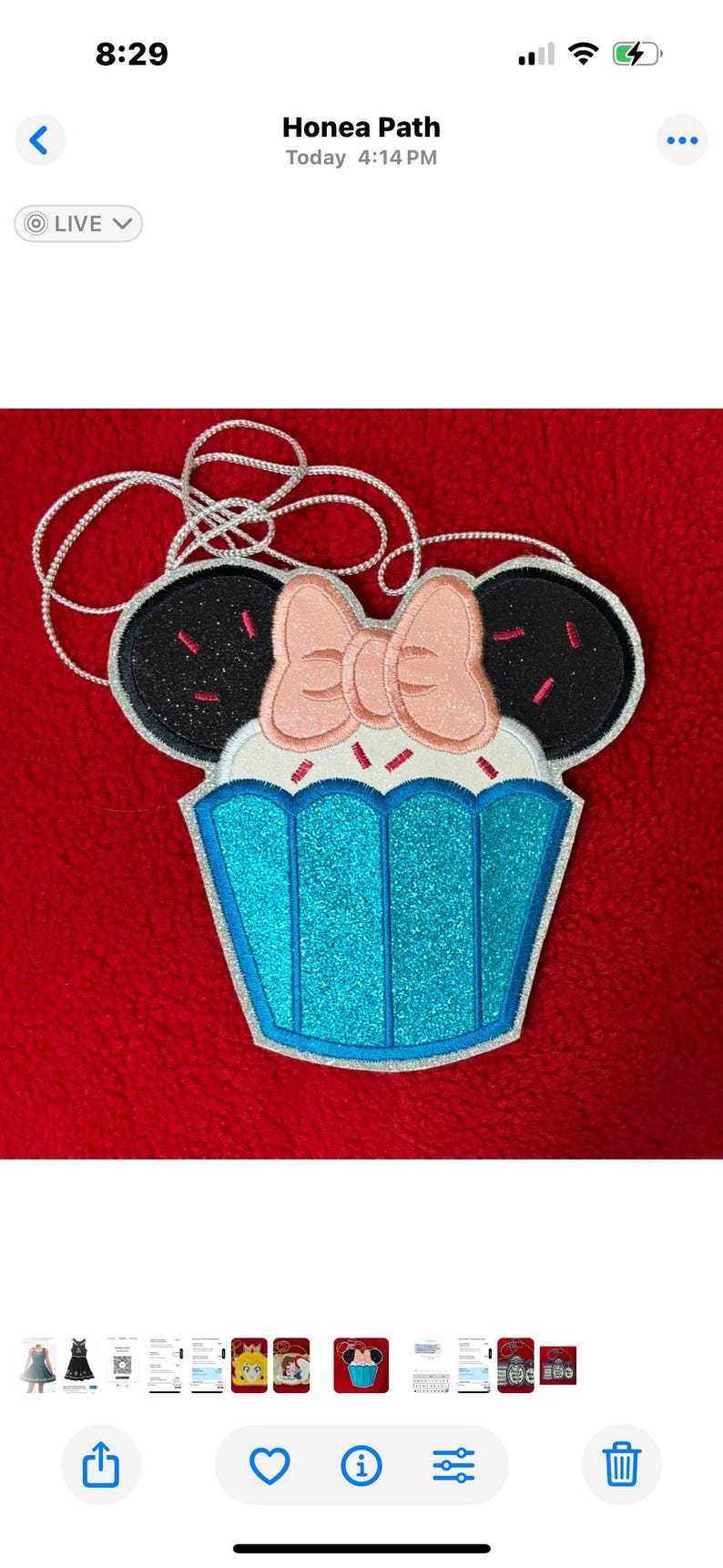 May include: A cupcake-shaped applique with black glitter ears and a pink bow. The cupcake has a blue glitter base and white frosting with pink sprinkles. A silver cord is attached for hanging.