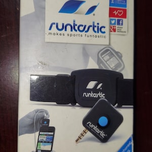 May include: A black and blue heart rate monitor for smartphones. The monitor is worn on the chest and connects to a smartphone via a headphone jack. The packaging includes the text "runtastic makes sports funtastic".