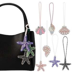 May include: A set of eight beaded bag charms featuring a variety of sea-themed designs, including starfish, seashells, and a pearl-encrusted seashell. The charms are attached to black, white, and pink cords.