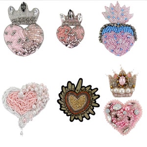 Può includere: Assortimento di sei toppe a forma di cuore con perline, con decorazioni a corona e ali. Le toppe sono rosa, bianche, blu, dorate e argentate.