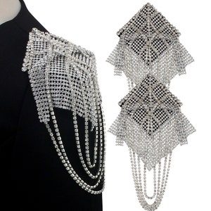 以下が含まれることがあります： ラインストーンのシルバーのショルダーストラップ2つと、ぶら下がっているチェーン。ストラップはラインストーンのメッシュでできており、正方形の形をしています。チェーンはラインストーンでできており、長さは約25cmです。