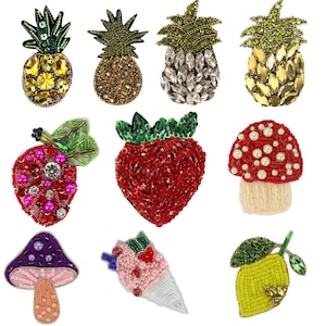 Op de afbeelding: Assortiment van kleurrijke, met kralen bezette strijkpatches, waaronder een ananas, aardbei, paddenstoel en citroen. Deze patches zijn perfect om kleding, tassen of andere accessoires een unieke touch te geven.