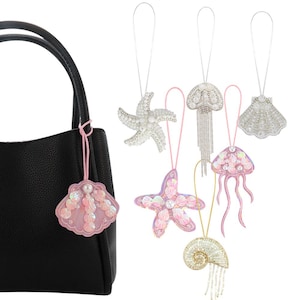 May include: A black handbag with a pink seashell charm. Various beaded sea creature ornaments, such as starfish, jellyfish, and shells, hang from strings. The ornaments are decorated with sequins and beads, in white, pink, and gold.