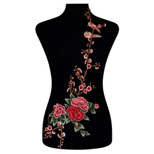 May include: An embroidered floral applique with red peonies, pink blossoms, and two birds on a branch. The design is set against a black background. This applique is suitable for clothing or craft projects, offering a decorative element.