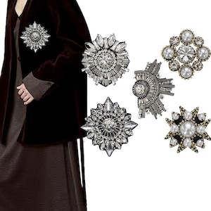 以下が含まれることがあります： 銀と金のトーンで、星、花、幾何学模様の5種類のラインストーンと真珠の装飾。