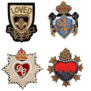 May include: Four embroidered patches with different designs. The first patch is black with gold embroidery and says "LOVED" with a bee inside a heart. The second patch is blue with gold embroidery and features a lion inside a shield with a crown on top. The third patch is white with gold embroidery and features a heart with a crown on top. The fourth patch is gold with red and black beads and features a heart with a crown on top.