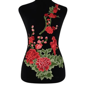 May include: Red embroidered applique featuring a floral design with two birds. The design includes red peonies, pink blossoms, and green leaves.
