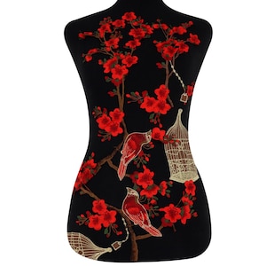 May include: Red embroidered applique featuring a floral design with birds and cages. The design is on a black fabric background.