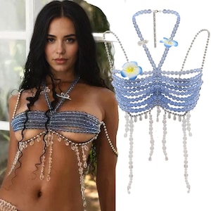 May include: A blue and clear beaded body chain with flower accents. The chain is made of small, round beads and has a delicate, feminine look.