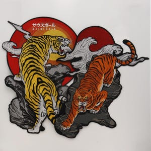 May include: An embroidered patch featuring two tigers on dark gray rocks against red and orange circular backgrounds. The left tiger is yellow with black stripes, and the right tiger is orange with black stripes. Text reads "サウスポール ORIGINALS".