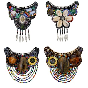 Puede incluir: Cuatro collares diferentes de cuentas con cuentas y piedras de varios colores. Los collares son todos negros y presentan una variedad de materiales, incluyendo conchas, piedras y cuentas.
