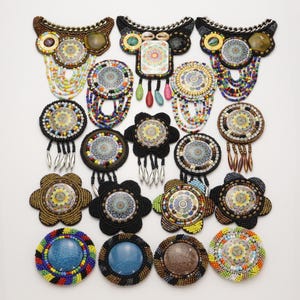 May include: A collection of seventeen handcrafted beaded brooches and necklaces featuring circular mandala-style printed centres, intricate seed bead embroidery, metallic chain accents, dangling bead fringes, and various colourful gemstone-like cabochons.