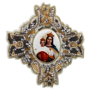 May include: A white fabric patch with a gold and silver beaded border. The centre of the patch features a printed image of the Virgin Mary holding a baby Jesus. The image is surrounded by a gold oval frame.