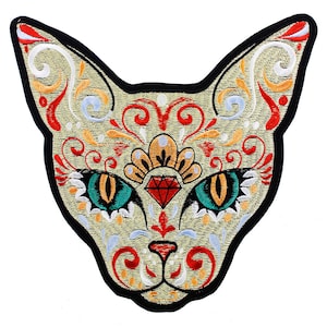 May include: Iron-on patch embroidered with a colourful, stylised cat face featuring a red jewel in the centre of its forehead. The cat's eyes are green and yellow, and the design is surrounded by intricate floral patterns.