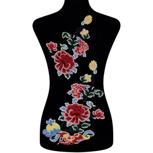 May include: Embroidered floral applique with pink, red, and yellow flowers on a black background. The flowers are arranged in a vertical line and have a delicate, feminine look.