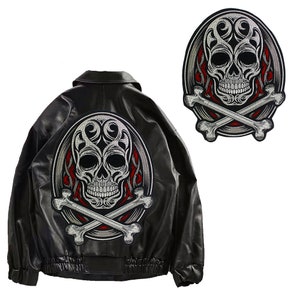 Può includere: Una giacca di pelle nera con una toppa ricamata in argento e rosso con un teschio e ossa incrociate sul retro.