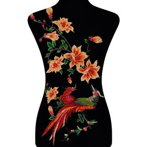 May include: Embroidered applique featuring a colourful bird with a long tail and orange flowers on a black background.