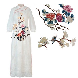 May include: Embroidered floral applique patches featuring a bird and branches. The patches depict pink, red, white, and blue flowers with green leaves. The bird is blue and white with a red beak.