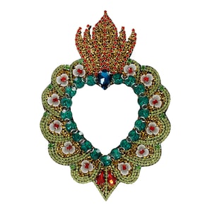 Peut inclure: Une ornement en forme de cœur orné de bijoux avec une couronne sur le dessus. Le cœur est fait de perles et de strass verts, dorés et blancs. La couronne est rouge et dorée.