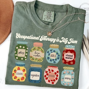 May include: Green t-shirt with the text "Occupational Therapy is My Jam" and a design of nine jars with different labels: "play", "fine motor", "ADLS", "visual motor", "learn", "cognition", "social", and "sensory".