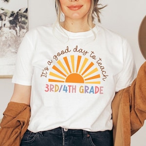 May include: White t-shirt with a colorful graphic of a sun and the text "It's a good day to teach 3rd/4th grade".