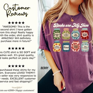 May include: Berry-coloured t-shirt featuring the text "Books are My Jam" and illustrations of jam jars. Each jar has a unique design and text, including "Endless TBR" and "Page Turner".