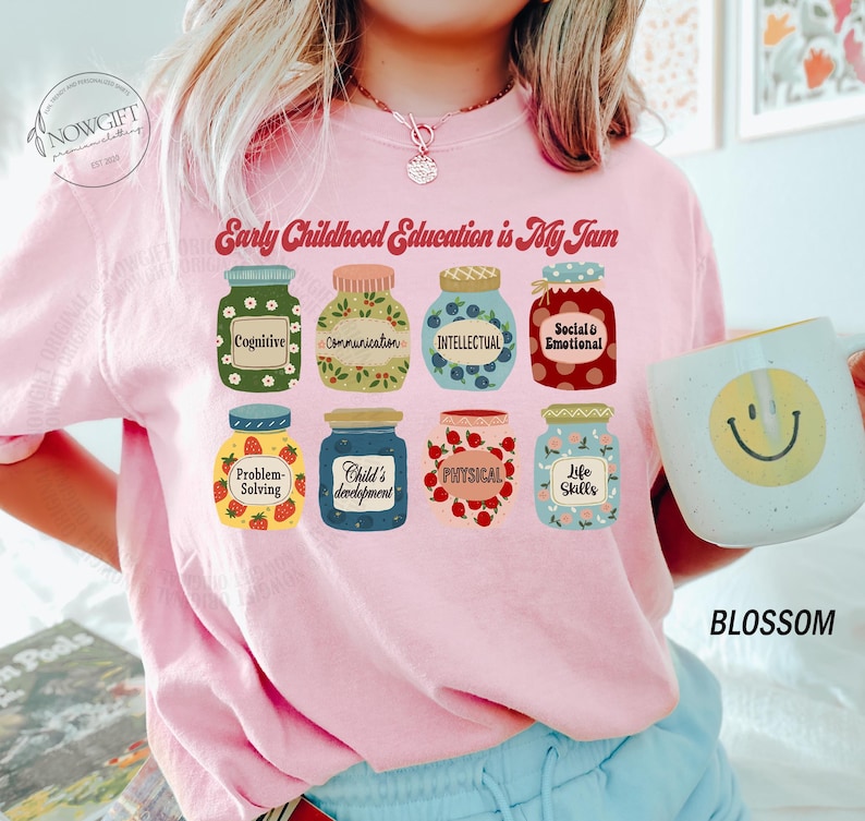 Puede incluir: Camiseta rosa con el texto "Early Childhood Education is My Jam" y un gr&aacute;fico de tarros con diferentes aspectos de la educaci&oacute;n de la primera infancia, como la cognici&oacute;n, la comunicaci&oacute;n, la intelectual, la social y la emocional, la resoluci&oacute;n de problemas, el desarrollo del ni&ntilde;o, la f&iacute;sica y las habilidades para la vida.