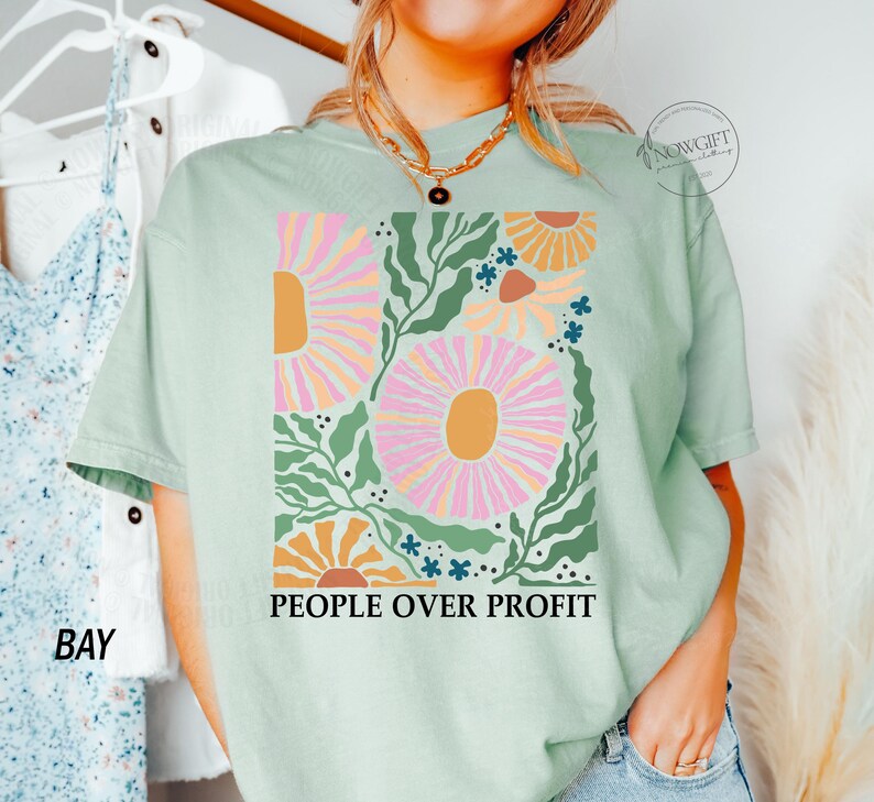 May include: A light green t-shirt with a floral design and the text "People Over Profit" printed on the front.