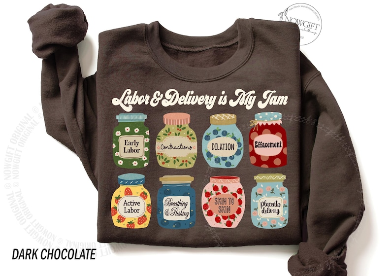 May include: A dark chocolate brown sweatshirt with the text "Labor & Delivery is My Jam" printed on the front. The text is surrounded by illustrations of jars of jam with different labels, such as "Early Labor", "Contractions", "Dilation", "Effacement", "Active Labor", "Breathing & Pushing", "Skin to Skin", and "Placenta Delivery".